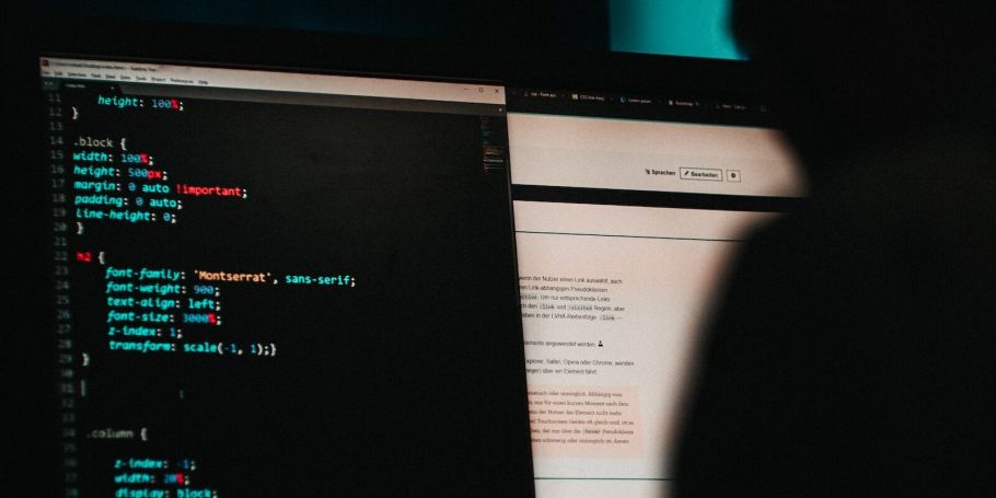 Hacker sitzt vor Bildschirm mit Code darauf