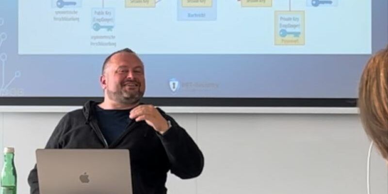 mario friedl vor einer leinwand mit einem verschlüsselungsdiagramm
